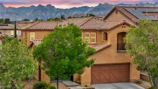 mediterranean / spanish home with a tile roof, an attached garage, stucco siding, a mountain view, and concrete driveway
