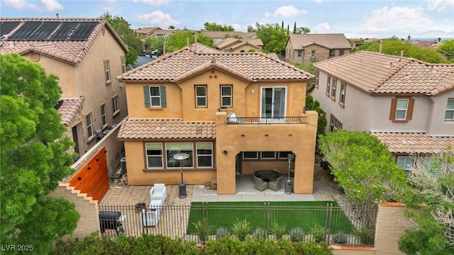 back of property featuring a fenced backyard, a tiled roof, a balcony, and stucco siding
