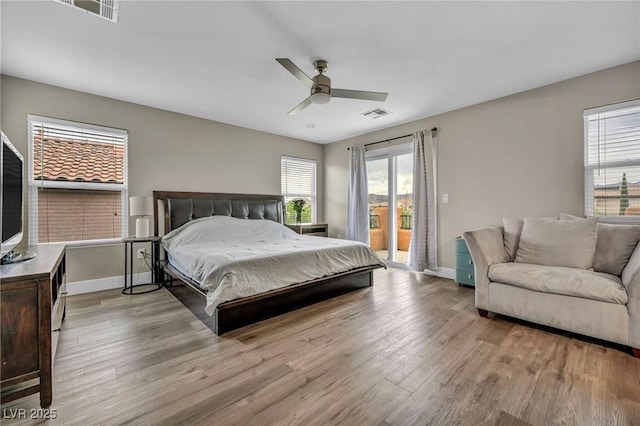 bedroom with access to outside, multiple windows, wood finished floors, and baseboards