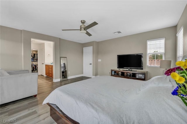 bedroom with wood finished floors, ceiling fan, baseboards, and a spacious closet