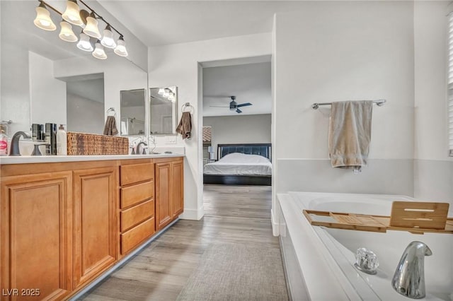 bathroom with wood finished floors, a ceiling fan, a tub, connected bathroom, and double vanity