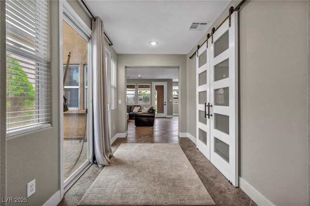 corridor with a barn door, baseboards, dark tile patterned flooring, and recessed lighting