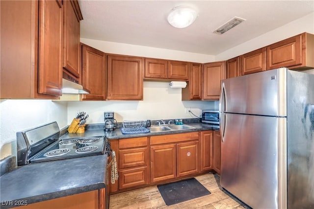 1553 Dorothy Ave Unit 4, Las Vegas, NV 89119 - kitchen with stainless steel appliances, under cabinet range hood, a sink, dark countertops, and brown cabinetry