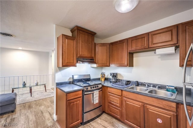 1553 Dorothy Ave Unit 4, Las Vegas, NV 89119 - kitchen with stainless steel gas range, brown cabinets, dark countertops, light wood finished floors, and a sink