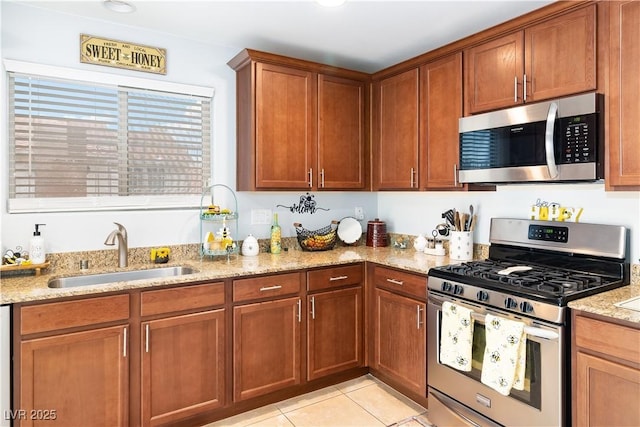 2213 Chandler Ranch Pl, Laughlin, NV 89029 - kitchen with stainless steel appliances, a sink, light stone counters, light tile patterned floors, and brown cabinetry