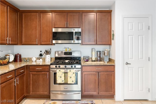 2213 Chandler Ranch Pl, Laughlin, NV 89029 - kitchen featuring stainless steel appliances, light stone countertops, light tile patterned floors, and brown cabinets