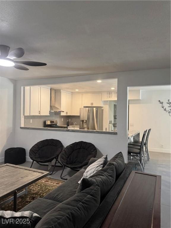 living room featuring baseboards, a ceiling fan, and recessed lighting