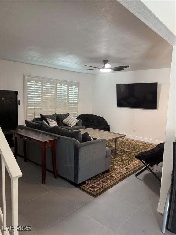 living room with a ceiling fan and tile patterned floors