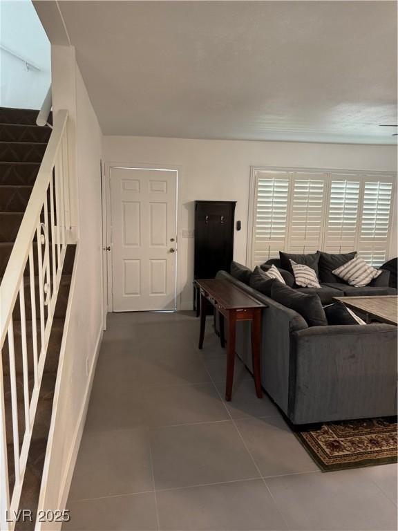 living room featuring stairs, tile patterned flooring, and baseboards