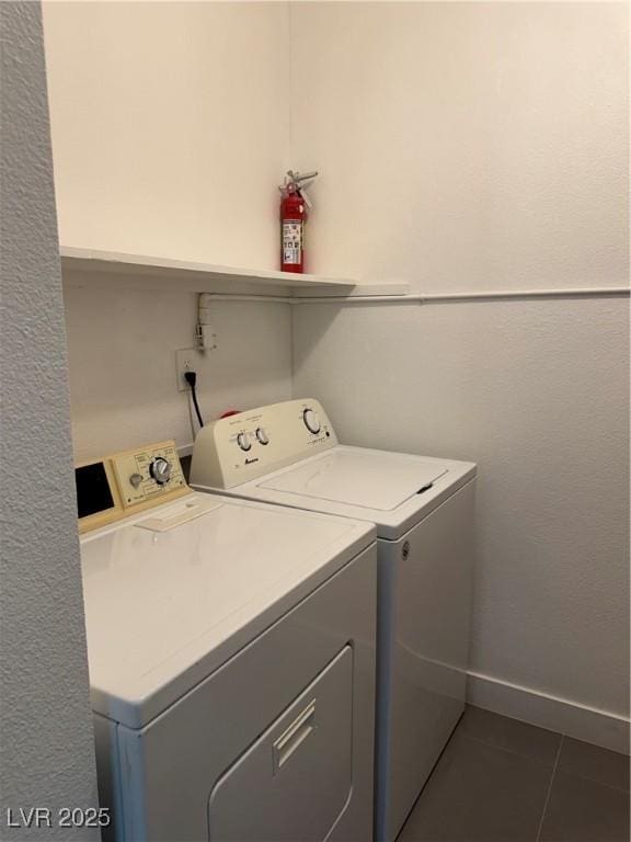 washroom featuring washing machine and dryer, dark tile patterned floors, and baseboards