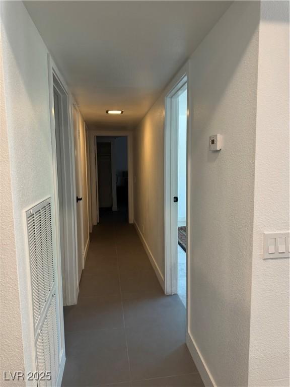 hall featuring tile patterned floors, baseboards, and a heating unit