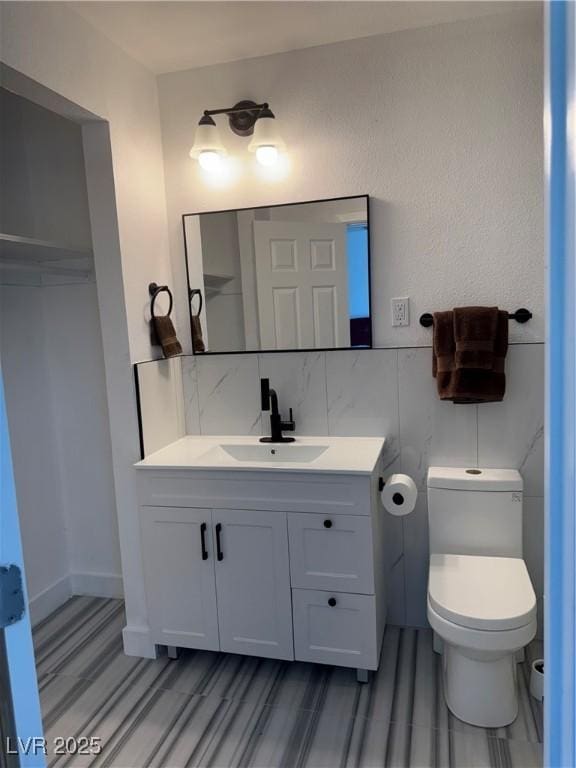 bathroom with toilet, vanity, wood finished floors, and decorative backsplash