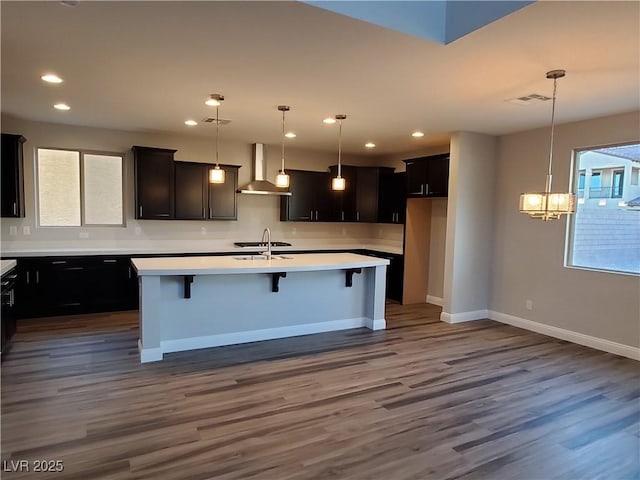 1027 Cambridge Park St, Las Vegas, NV 89148 - kitchen featuring wall chimney exhaust hood, a center island with sink, a chandelier, dark wood-style floors, and a breakfast bar