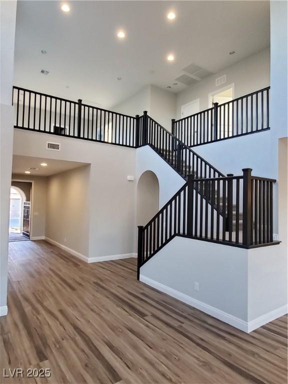 1027 Cambridge Park St, Las Vegas, NV 89148 - staircase featuring a towering ceiling, wood finished floors, baseboards, arched walkways, and recessed lighting