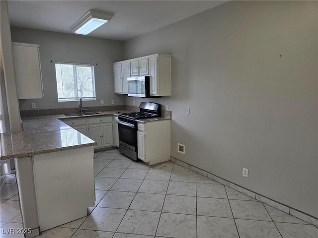 kitchen with range with gas cooktop, stainless steel microwave, a sink, a peninsula, and white cabinetry
