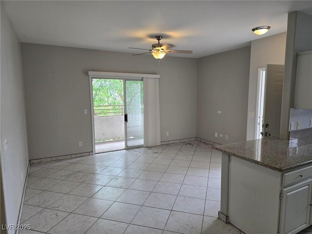 empty room featuring ceiling fan, light tile patterned floors, and baseboards