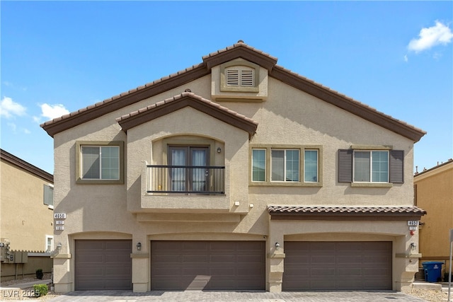 view of property with stucco siding, a garage, and a tiled roof