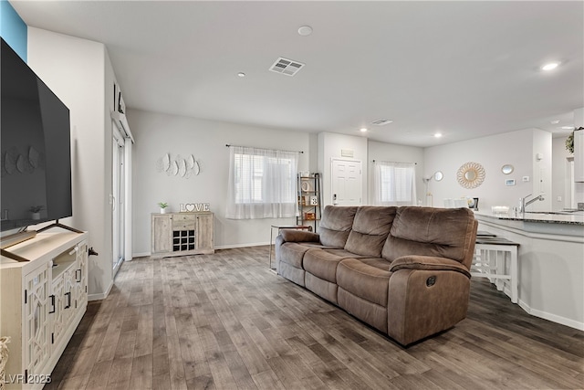 living room with wood finished floors, healthy amount of natural light, recessed lighting, and baseboards