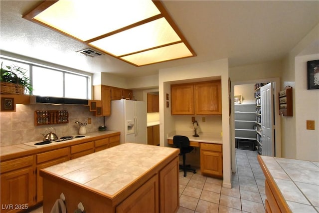 kitchen with white appliances, tile counters, brown cabinets, and backsplash