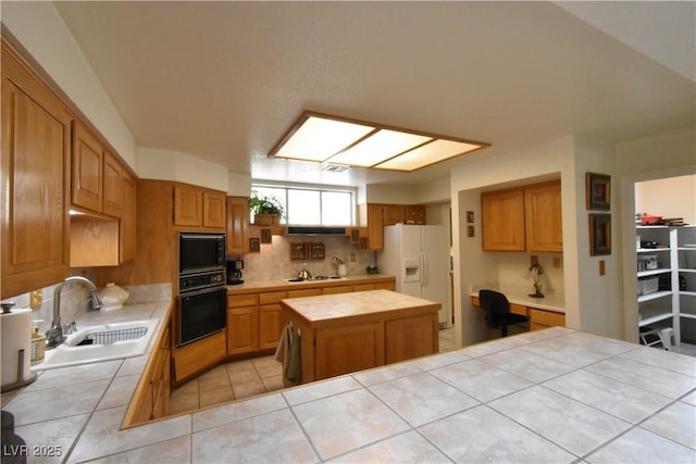 kitchen featuring black appliances, tile countertops, a sink, tasteful backsplash, and a kitchen island