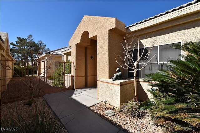 view of home's exterior with stucco siding and fence