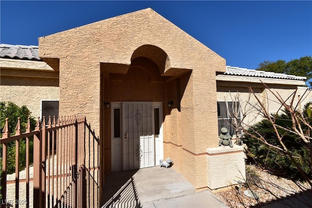 property entrance with fence and stucco siding
