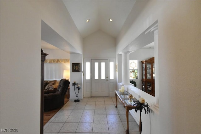 foyer entrance with light tile patterned floors, ornate columns, and lofted ceiling