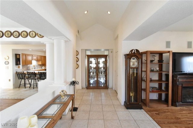 entryway with decorative columns, light tile patterned floors, vaulted ceiling, and recessed lighting