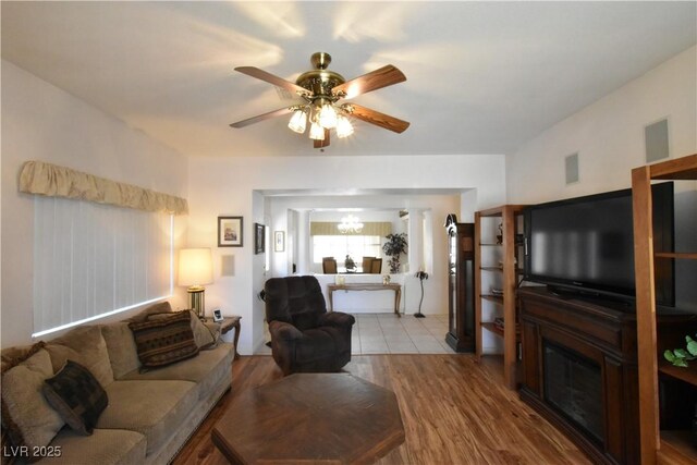 living area featuring ceiling fan, wood finished floors, and a glass covered fireplace