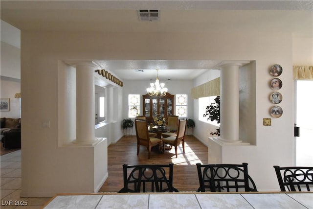 dining area featuring ornate columns, a chandelier, and plenty of natural light