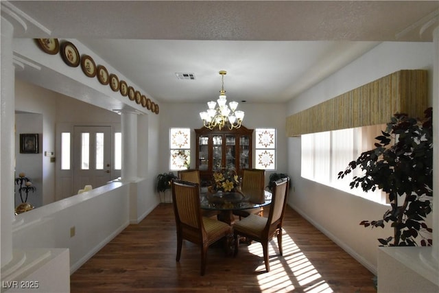 dining room featuring a chandelier, baseboards, healthy amount of natural light, and wood finished floors
