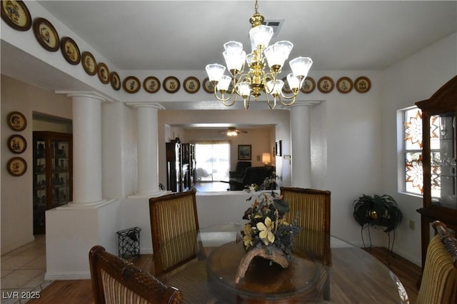 dining space featuring ornate columns, a chandelier, and wood finished floors