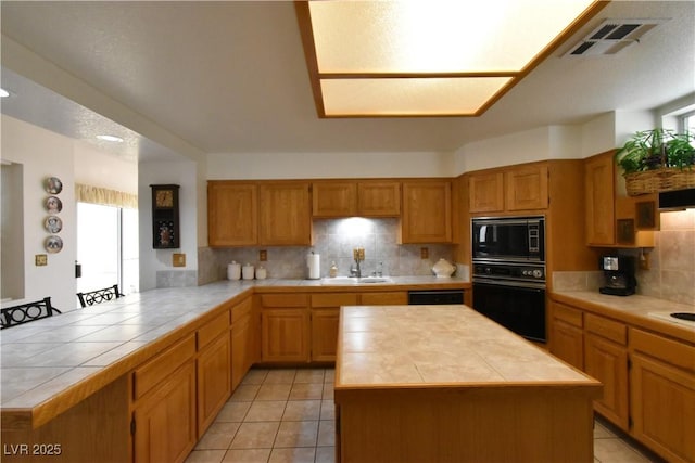 kitchen featuring black appliances, tile counters, a peninsula, backsplash, and light tile patterned floors