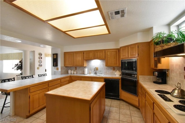 kitchen with black appliances, tile counters, a sink, a peninsula, and tasteful backsplash