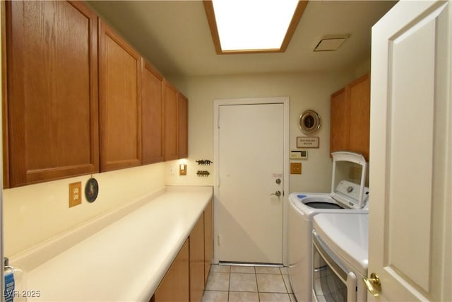 clothes washing area with cabinet space, independent washer and dryer, and light tile patterned floors