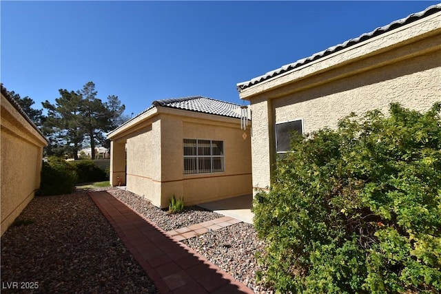 view of side of home with stucco siding and a patio