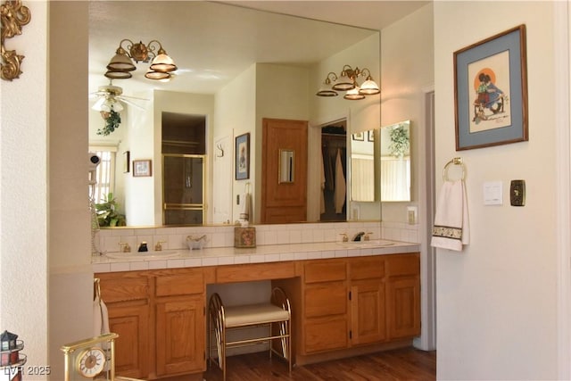 full bath featuring backsplash, a shower stall, double vanity, and wood finished floors