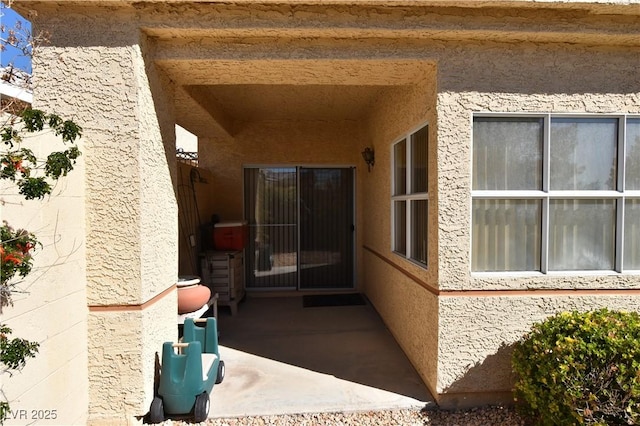 property entrance with stucco siding and a patio area