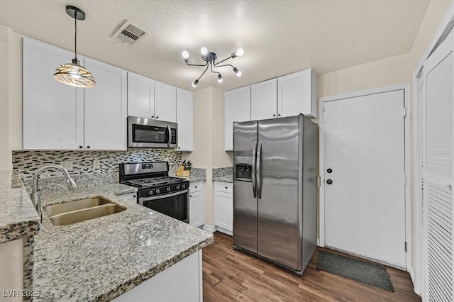 4820 Integrity St, North Las Vegas, NV 89031 - kitchen with stainless steel appliances, a sink, white cabinetry, dark wood finished floors, and light stone counters
