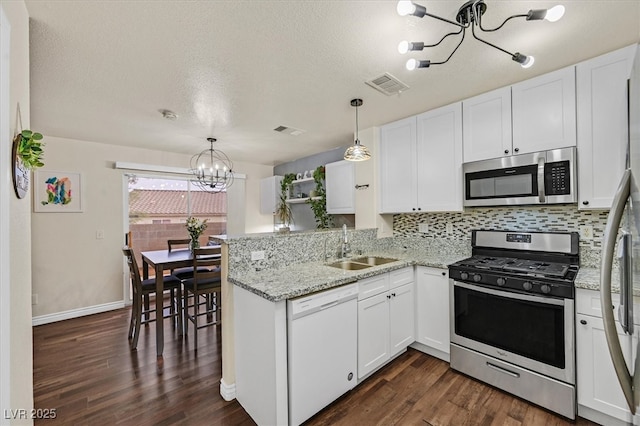 4820 Integrity St, North Las Vegas, NV 89031 - kitchen with appliances with stainless steel finishes, a chandelier, a sink, a peninsula, and white cabinets