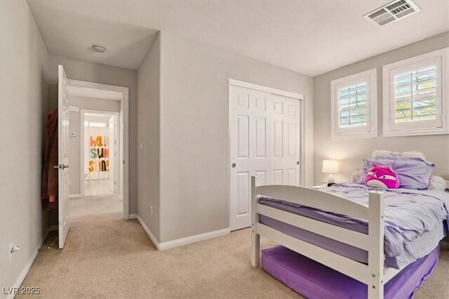 bedroom featuring light colored carpet, baseboards, and a closet