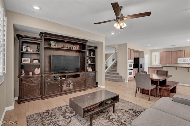 living room featuring light wood-style flooring, a ceiling fan, baseboards, stairs, and recessed lighting