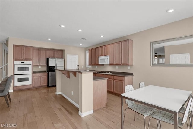 3141 Monet Sunrise Ave, Henderson, NV 89044 - kitchen with white appliances, light wood-style floors, a kitchen island with sink, baseboards, and recessed lighting