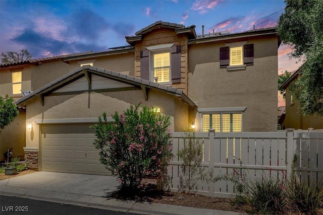 traditional-style house featuring stucco siding, fence, an attached garage, and driveway