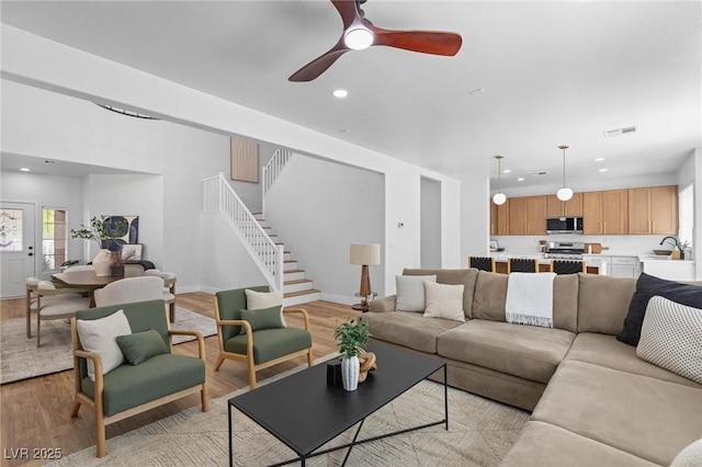 living room with stairway, light wood-type flooring, plenty of natural light, ceiling fan, and recessed lighting
