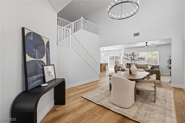 dining space with stairway, wood finished floors, ceiling fan, baseboards, and a high ceiling