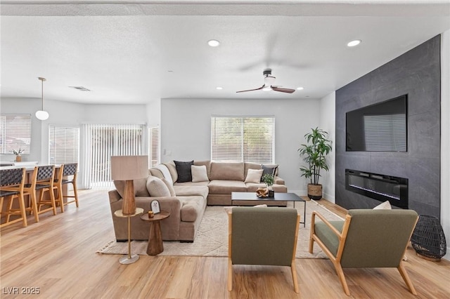 living area with light wood finished floors, a ceiling fan, recessed lighting, and a fireplace