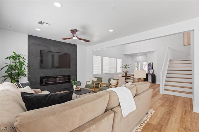 living room with stairway, light wood finished floors, ceiling fan, recessed lighting, and a fireplace