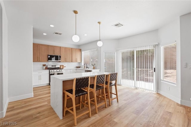 kitchen with appliances with stainless steel finishes, baseboards, light wood-type flooring, and recessed lighting
