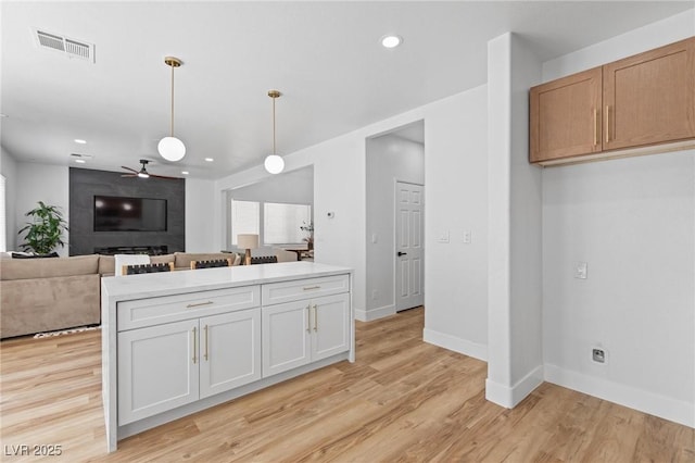 kitchen with a ceiling fan, baseboards, decorative light fixtures, light wood finished floors, and white cabinetry